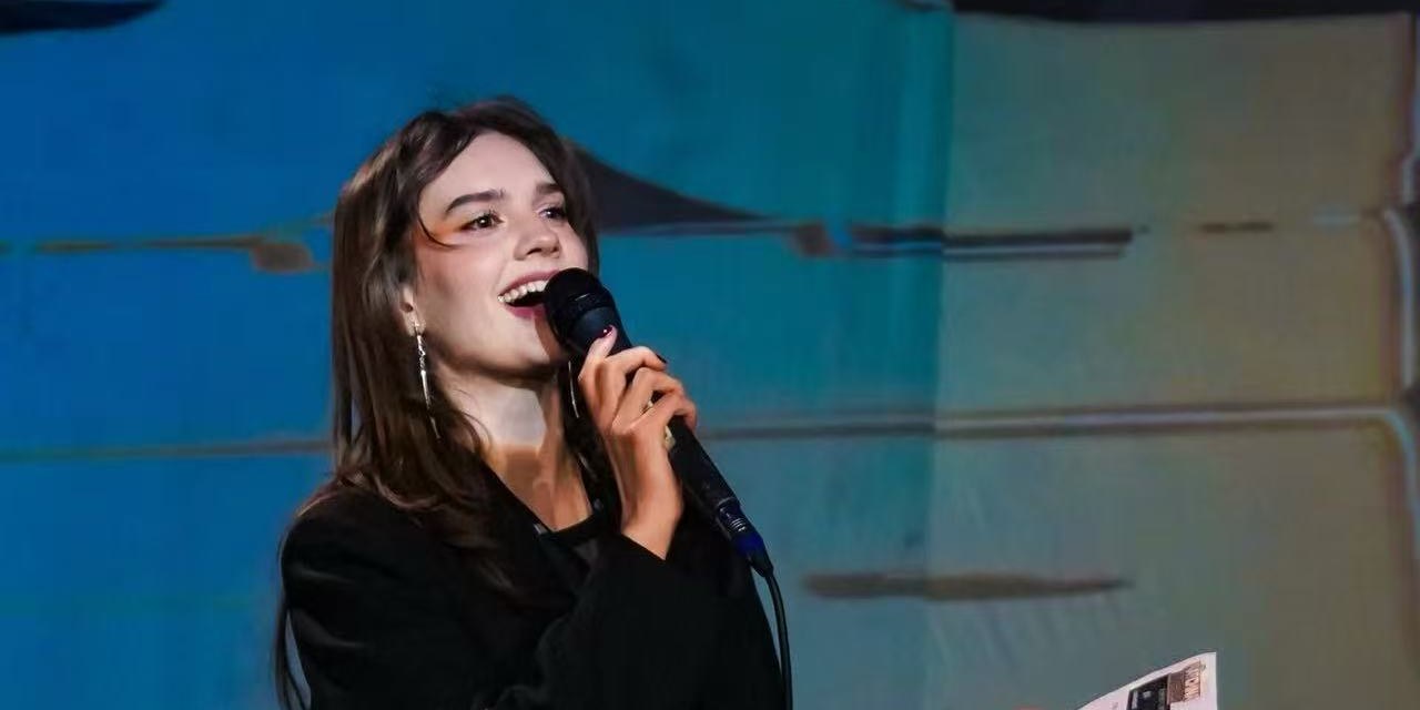 A young singer performing on stage with a microphone